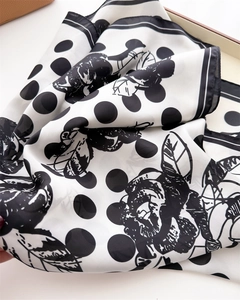 Dettaglio di un foulard in seta con classici pois neri e stampe floreali di rose eleganti