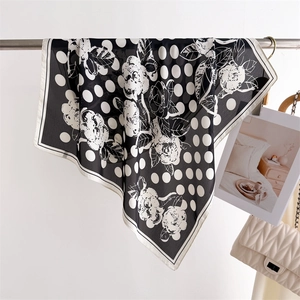 Sciarpa di seta a pois e floreale appesa accanto a elegante borsa trapuntata bianca