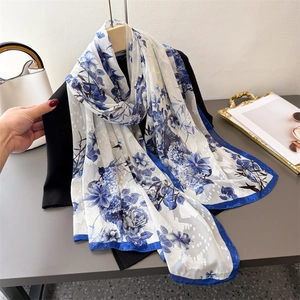 Élégant foulard en soie blanc à fleurs bleues présenté sur un vêtement noir chic