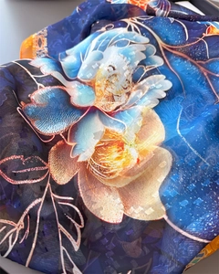 Détail du foulard en soie à imprimé floral bleu foncé et orange avec texture translucide