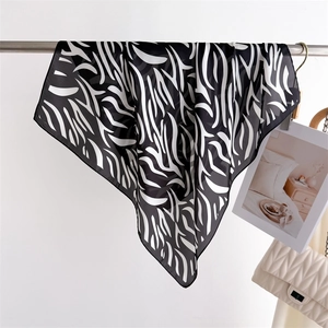 Detail of elegant black and white zebra print silk scarf draped near a luxury handbag