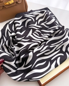 Close-up of zebra print silk scarf draped over a brown leather handbag