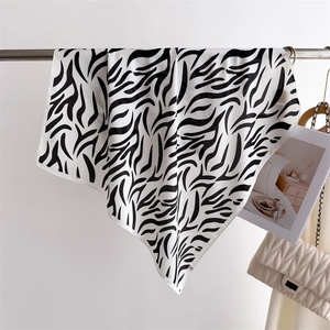 Detail of silk scarf with zebra print draping next to a luxury quilted handbag