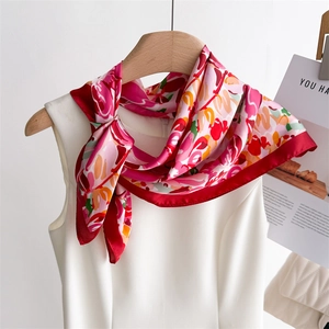 Detail of silk-texture square scarf with red floral print knotted on white dress