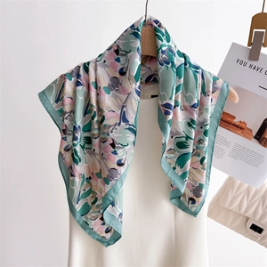 Elegant floral print silk scarf in green and pink draped on a minimalist white dress