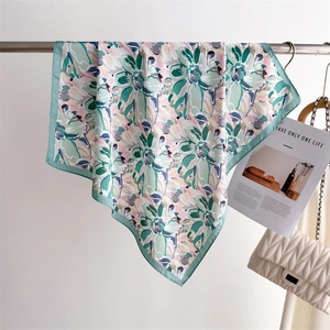 Detail of floral printed silk scarf in mint green and pink hung on a metal rack