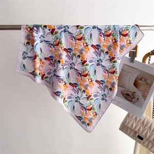 Detail view of floral silk scarf with purple edges hanging on a metal rod