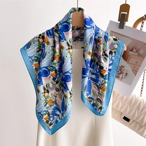 Detail of blue floral silk scarf hanging on a wooden hanger with a soft satin luster