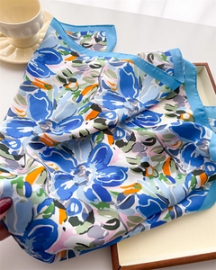 Macro detail of sky blue floral print silk scarf with artistic satin finish texture