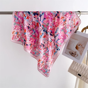 Detail of elegant pink floral silk scarf draped with a stylish white quilted chain bag