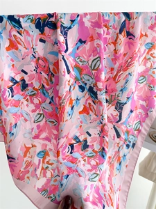 Close-up of abstract floral print and smooth rolled edges on the pink silk neckerchief