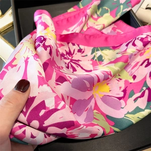 Macro detail of silky floral square scarf with elegant pink and fuchsia flower patterns