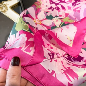 Detail view of pink silk scarf showing premium floral print and smooth satin texture