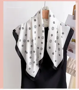 Détail du foulard en soie avec motif de camélia noir classique sur un tissu blanc élégant