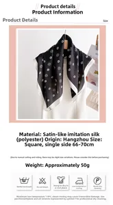 Détail d'un foulard carré en satin noir à motif camélia blanc avec bordures finies