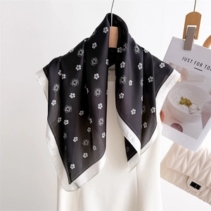 Élégant foulard en soie noir et blanc à imprimé camélia suspendu sur un cintre