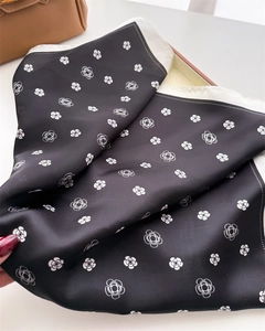 Détail d'un carré de soie avec imprimé floral de camélia blanc sur tissu noir de qualité