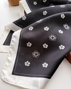 Détail d'un foulard en soie avec imprimés camélia blanc et texture satinée lisse