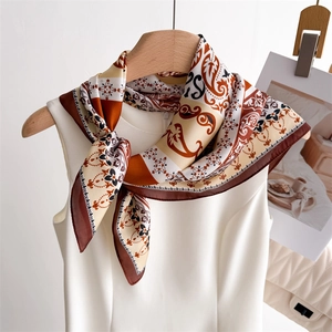 Detail of elegant paisley print silk square scarf styled on a white dress collar