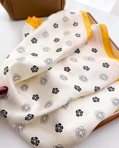 Gros plan sur un foulard carré en soie avec imprimés camélia et bordures jaunes chics