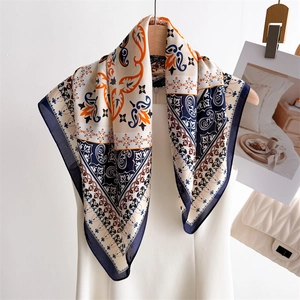 Elegant silk scarf with paisley print in orange and blue, draped on a white dress