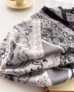 Detail of silk-like square scarf with grey paisley pattern and black border design
