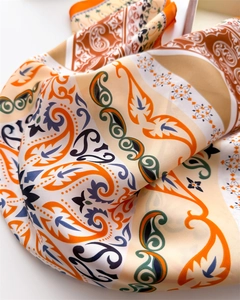 Close-up of silk scarf with orange and navy paisley patterns and smooth texture