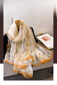 Detail of floral chiffon scarf with yellow print and orange edges hanging on a hanger