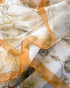 Close-up of lightweight floral silk scarf with warm orange plaid borders and soft texture