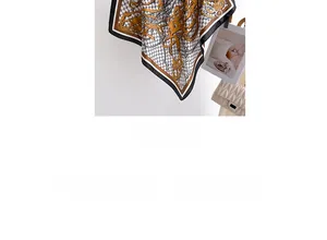 Detail of elegant black and gold silk scarf featuring classic chain pattern and soft texture