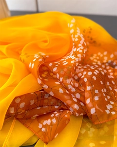 Close-up of lightweight orange chiffon scarf featuring elegant white floral prints