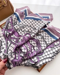 Detailed view of luxury silk scarf with equestrian chain prints in a wooden tray