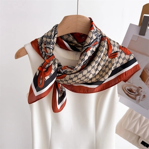 Elegant silk scarf with retro chain print and satin finish tied on a white collar
