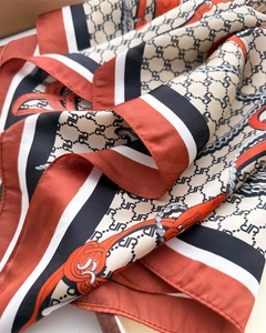 Detailed close-up of equestrian chain print silk scarf with smooth satin texture folds