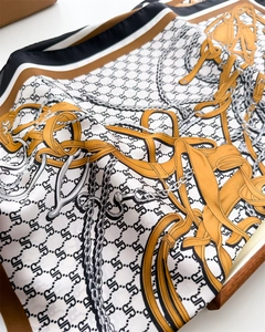 Detail of silk square scarf featuring equestrian chain print and smooth drape texture