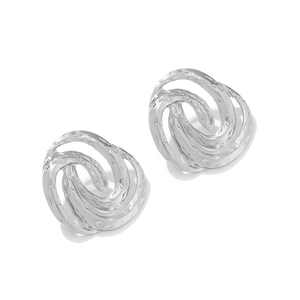 Macro detail of silver spiral earrings with textured hammered finish and fluid metal design