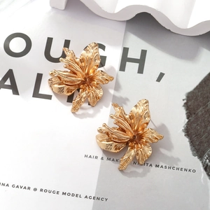 Close-up of golden vintage flower earrings with detailed 3D petals on a fashion magazine