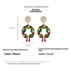 Detail view of Christmas wreath earrings with green leaves, red bow and pearl studs