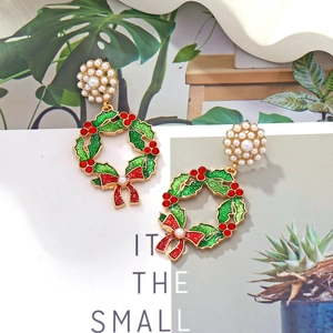 Detail of Christmas wreath earrings with faux pearls and festive red bow on a card