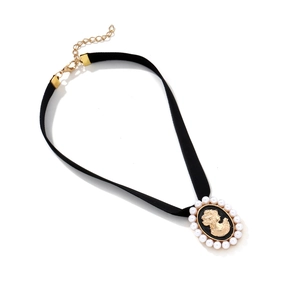 Detailed close-up of a vintage black velvet choker with a pearl cameo pendant