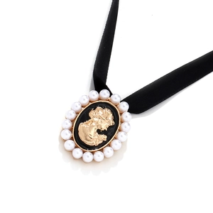 Macro view of French vintage choker with pearl cameo pendant on black velvet ribbon