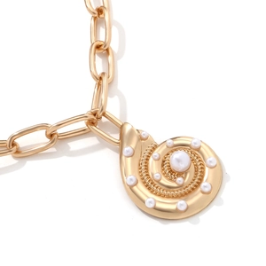 Macro shot of gold shell pendant necklace with white pearls on a chunky metal chain
