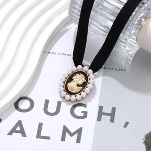 Close-up of a velvet choker with a gold portrait pendant and pearl edge detailing