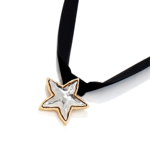 Macro shot of two-tone gold and silver star pendant on a black velvet choker necklace