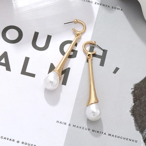 Détail de boucles d'oreilles dorées avec perles blanches sur magazine de mode