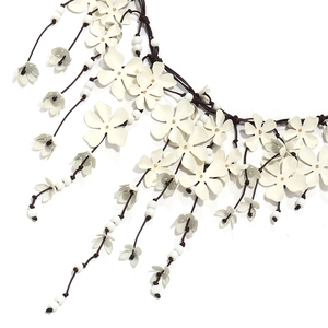 Macro detail of multi-layered white floral necklace with beads and fringe accents