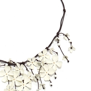 Detailed close-up of handmade white flower fringe necklace with layered woven cord