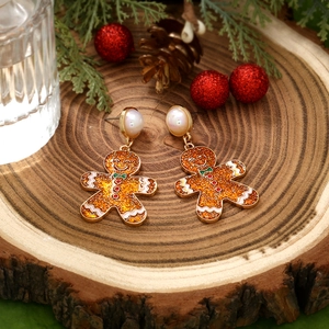 Christmas gingerbread man earrings with enamel finish and pearl studs on festive background