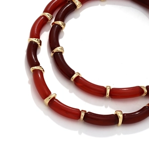 Detailed macro view of resin bamboo joint necklaces with red beads and gold spacers