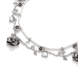 Close-up of layered faux pearl necklace with silver rose vines and floral details